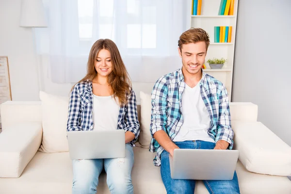 Mutlu genç adam ve iki dizüstü bilgisayarlarda çalışan kadın — Stok fotoğraf