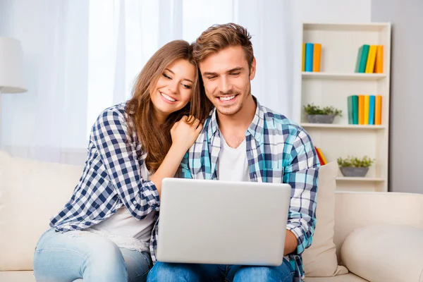 Portrait of happy young family sitting on sofa with laptop — Stock Photo, Image