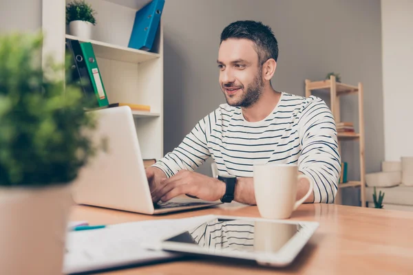 Hombre guapo sentado en su oficina y trabajando en el portátil — Foto de Stock