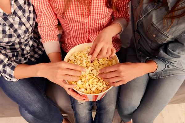 Close up photo of three women sitting on couch and eating popcor — Stock Photo, Image