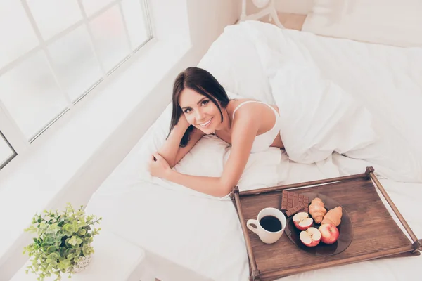 Chica feliz en la cama con bandeja de madera con sabroso breackfast — Foto de Stock