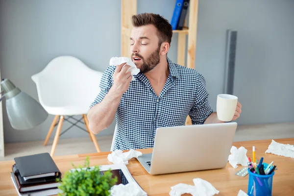 Kranker Geschäftsmann hält Tasse heißen Tee und niest in Gewebe — Stockfoto