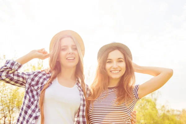 Portrait of two pretty girls in hats walking in the park — Stock Photo, Image