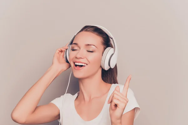 Vacker ung kvinna lyssnar musik i hörlurar och sjunga — Stockfoto