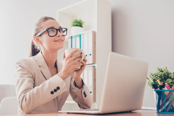 Femme de l'esprit dans des lunettes rêvant avec une tasse de café pendant son b — Photo