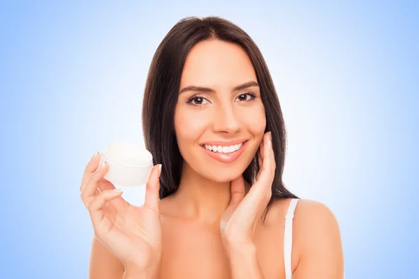 Retrato de mulher bonita segurando frasco e aplicando creme sobre ela — Fotografia de Stock