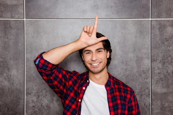Lustiger junger Mann zeigt Zeichen Verlierer mit Fingern in der Nähe der Stirn ein — Stockfoto