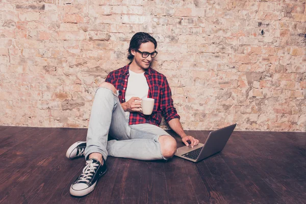 Jovem sentado no chão com laptop e beber café — Fotografia de Stock