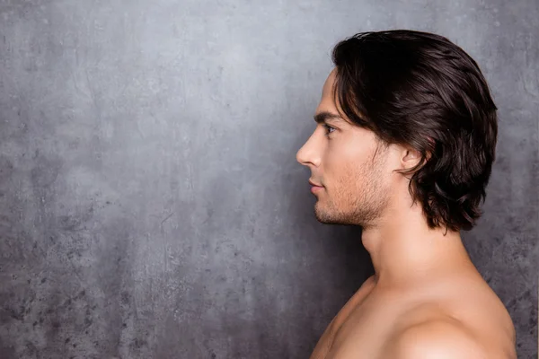 Portrait of side-view of young man with black hair near gray wal — Stock Photo, Image