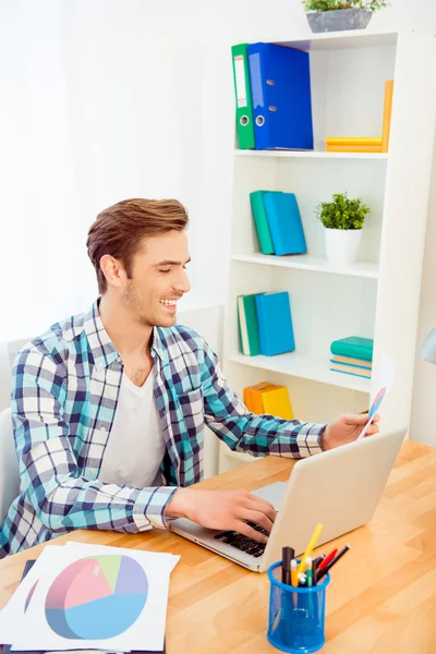 Portret van gelukkige jonge man die werken met de laptop en diagrama — Stockfoto