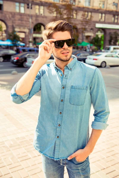 Stijlvolle jonge man lopen en houd zijn bril — Stockfoto