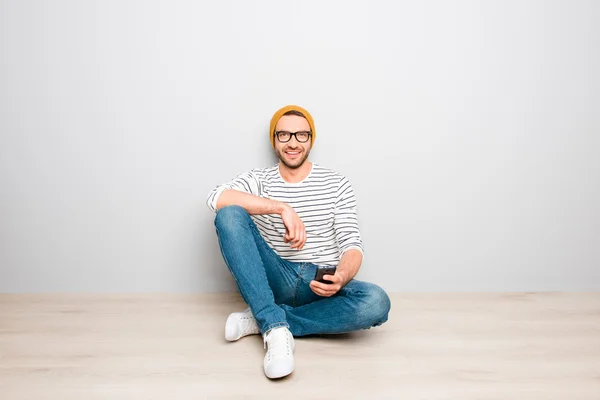 Bonito hipster homem em boné amarelo e óculos de digitação sms — Fotografia de Stock