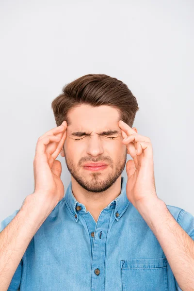 Handsome young tired man with migraine touching head — Stock Photo, Image