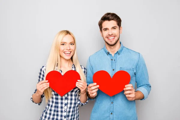 Retrato de hombre y mujer sonrientes sosteniendo dos corazones de papel rojo — Foto de Stock