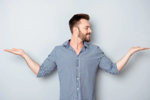 Cheerful young man chosing between products in both hands — Stock Photo, Image