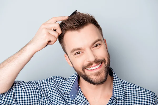 Handsome happy young man combing his hair — Stock Photo, Image