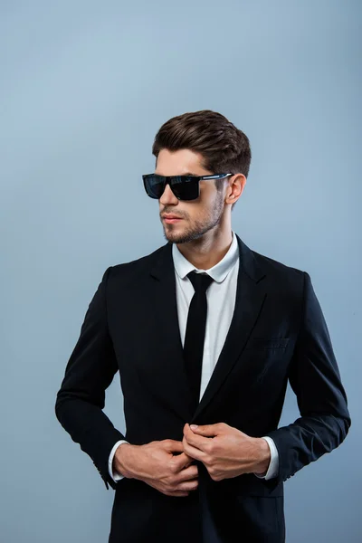Hombre de negocios exitoso en gafas negras abotonando su traje — Foto de Stock