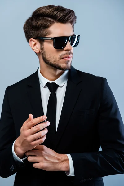 Handsome businessman in black suit and glasses fastening buttons — Stock Photo, Image