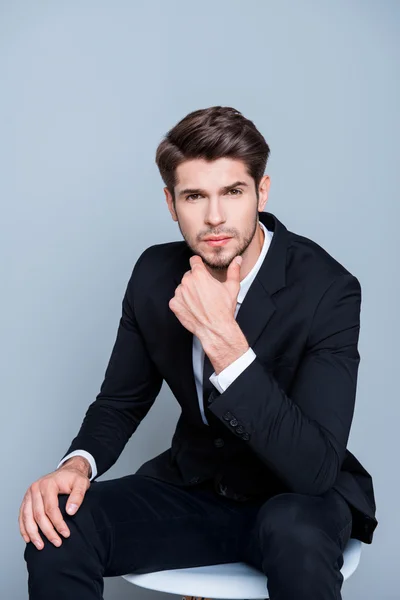 Portrait of ponder man in suit  sitting on chair and touching ch — Stock Photo, Image