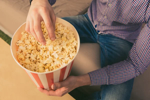 Close-up foto van jonge man eten popcorn thuis — Stockfoto