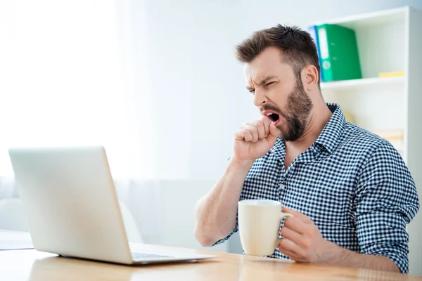 Joven empresario bostezando y bebiendo café para ser enérgico — Foto de Stock