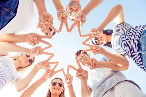 Gelukkige groep jonge mensen die vingerbewegingen tonen en op zoek zijn — Stockfoto