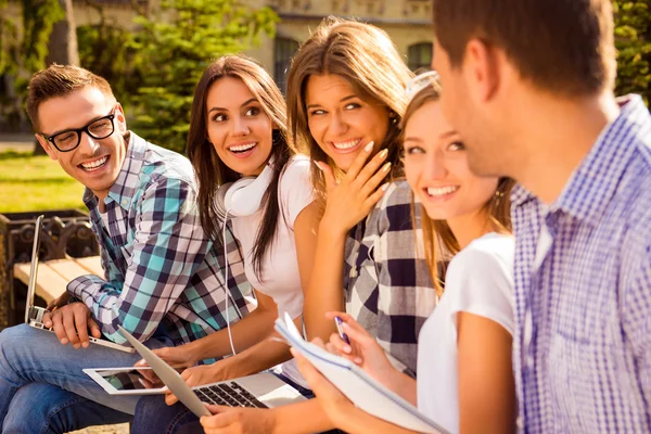 Cinq souriants heureux beaux camarades de classe parler et assis sur b — Photo