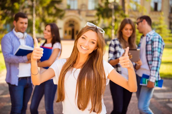 Glada lyckliga flicka som står nära universitet och hennes vänner och — Stockfoto