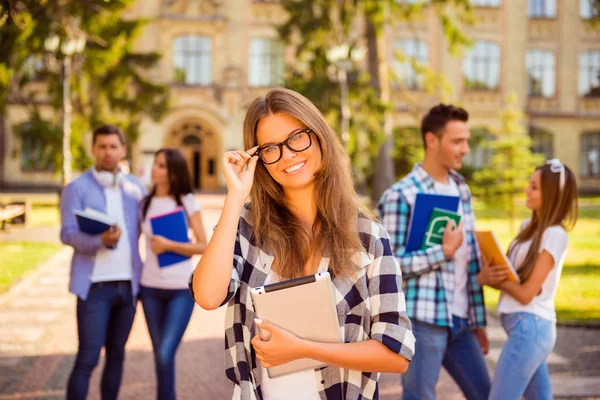 Smart glad tjej står nära universitet och hennes vänner och ad — Stockfoto