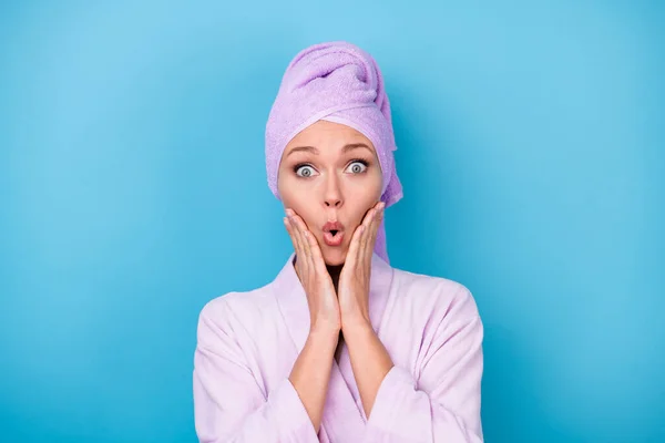 Fotografie hezké dívky ruce tváře šok výraz nosit fialové ručník turban župan izolované modré barvy pozadí — Stock fotografie