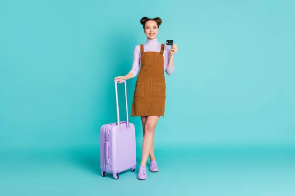 Full body foto van aantrekkelijke vrolijke positieve twee broodjes dame passagier betalen voor internationale reizen plastic kaart houden lila bagage slijtage lente outfit geïsoleerde turquoise kleur achtergrond — Stockfoto