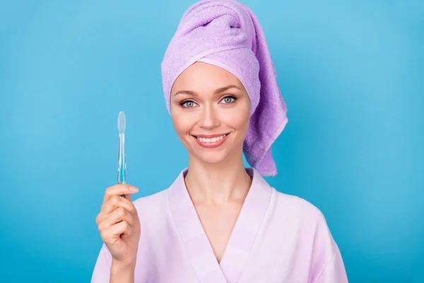 Foto de mulher jovem bonito segurar escova de dentes olhar câmera desgaste toalha violeta turbante banho roupão isolado azul cor fundo — Fotografia de Stock