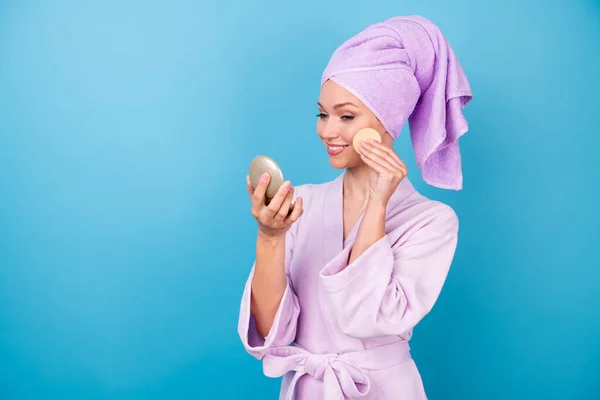 Фото милой юной леди держать взгляд зеркало хлопчатобумажная губка сияющий улыбающийся носить фиолетовый полотенце банный халат изолированный синий цвет фона — стоковое фото