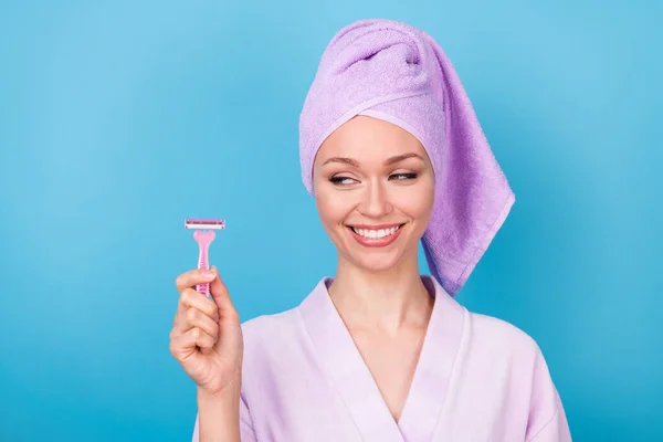 Foto de señora linda mirada lado mantenga hoja de afeitar rosa desgaste púrpura toalla turbante bata de baño aislado fondo de color azul — Foto de Stock