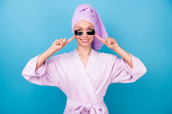 Foto de menina bonita indicar dedos olho manchas desgaste roxo toalha turbante banho roupão isolado azul cor fundo — Fotografia de Stock