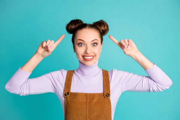 Foto de linda divertida loca feliz dama alegre nuevo peluquero increíble coiffure dedos índice dirigir dos bollos encantadores usan suéter violeta marrón en general aislado vivo color turquesa fondo — Foto de Stock