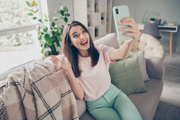 Retrato fotográfico de una mujer haciendo videollamadas saludando con la mano sonriendo con la boca abierta sosteniendo el teléfono en la mano en interiores — Foto de Stock
