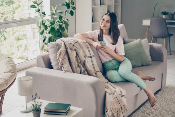 Foto portret van bedachtzame vrouw kijken in het raam glimlachende telefoon met twee handen binnen — Stockfoto