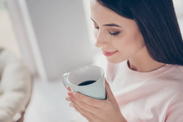 Foto portret van vrouw met gesloten ogen genieten van mooie geur van 's morgens koffie holding cup in twee handen binnen — Stockfoto