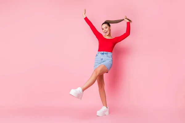 In voller Länge Foto von funky attraktive Dame schlanke Form Figur Arme Bein angehoben tanzen tragen rote offene Schultern Hemd Mini-Jeansrock Schuhe isoliert pastellrosa Farbe Hintergrund — Stockfoto