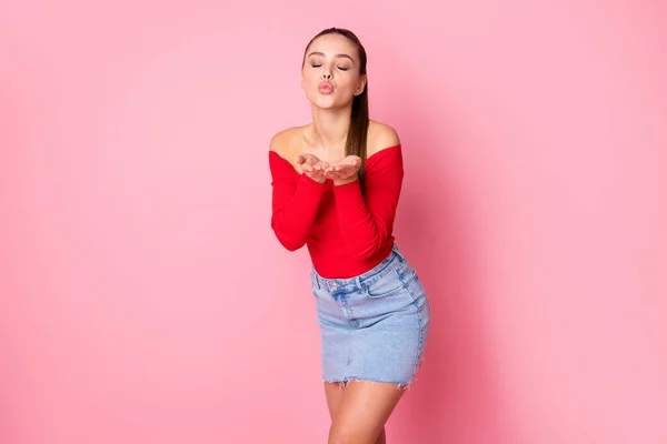 Foto van vrij mooie aantrekkelijke dame verzenden lucht kus lege ruimte houden open armen tedere gevoelens dragen casual rood open schouders shirt mini denim rok geïsoleerde pastel roze kleur achtergrond — Stockfoto