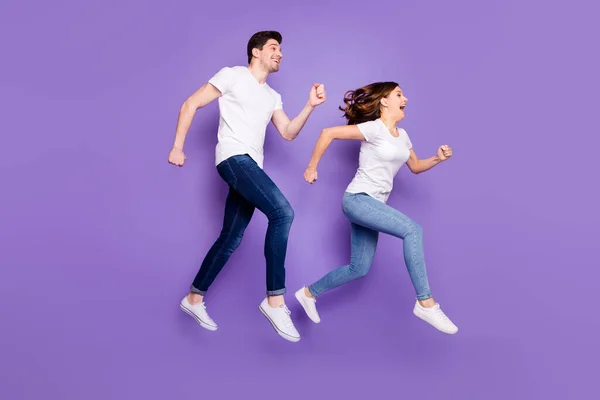 Полная длина профиля фото симпатичная женщина красивый парень прыжки высоко спортивные соревнования работает быстро закончить пару гонки носить повседневные футболки джинсы обувь изолированный фиолетовый цвет фона — стоковое фото