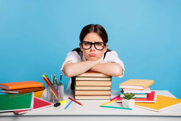 Photo of frustrated university student girl sit table put hands head pile stack copybook dislike many graduate homework wear white blůza black uniform isolated blue color background — Stock fotografie
