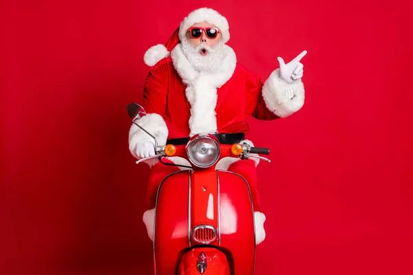 Foto do avô aposentado passeio de barba branca retro scooter choque direto dedo espaço vazio encontrar transporte curioso desconto desgaste x-mas traje casaco tampão de vidro solar isolado cor vermelha fundo — Fotografia de Stock