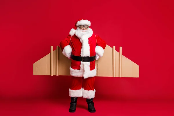 Foto de tamaño completo del cuerpo del abuelo retirado barba blanca jetpack listo inicio vuelo largo polo norte viaje desgaste traje de santa x-mas abrigo gafas diadema aislado color rojo fondo — Foto de Stock