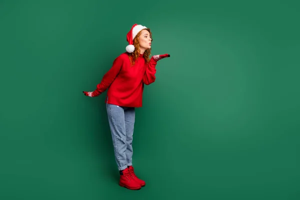 Perfil de comprimento total foto de senhora enviar ar beijo espaço vazio desgaste vermelho pulôver x-mas cap jeans calçado isolado cor verde fundo — Fotografia de Stock