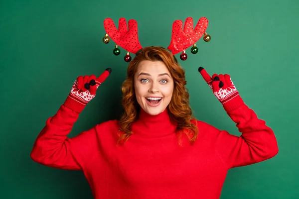 Fotografie legrační mladé dívky přímé prsty hlava rohy nosit červené svetr rukavice sobí parohy izolované zelené barvy pozadí — Stock fotografie
