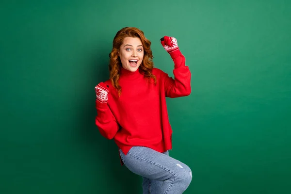 Foto gila gadis muda mengangkat tangan lutut terbuka mulut memakai pullover merah sarung jins terisolasi warna hijau latar belakang — Stok Foto