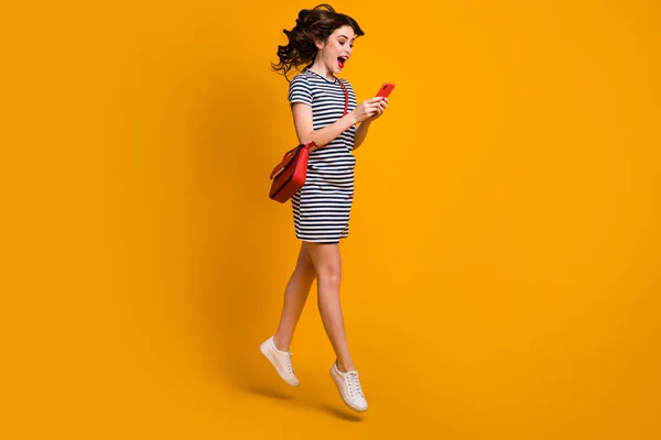 Komik kadının tam boy profil fotoğrafı yükseğe zıpla telefon satışı sezonu açılış reklamı açık ağız, günlük çizgili kısa debriyaj ayakkabılar, izole edilmiş sarı arka plan. — Stok fotoğraf