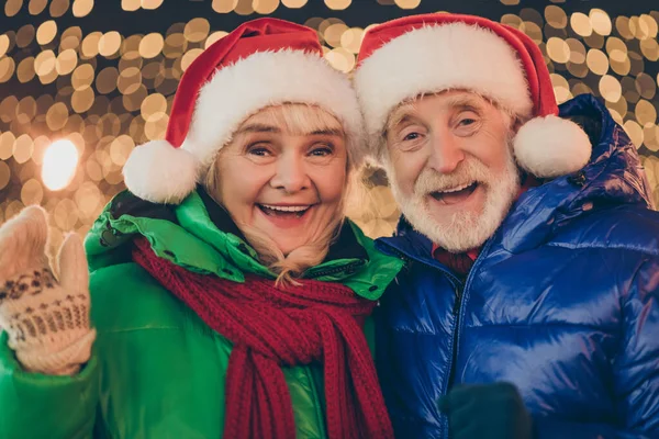 Foto av familj två medlemmar pensionerad man kvinna möte mormor våg hand hälsning gratulera granne vänta x-mas magi mirakel bära rock huvudbonad natt gata belysning rättvis utomhus — Stockfoto